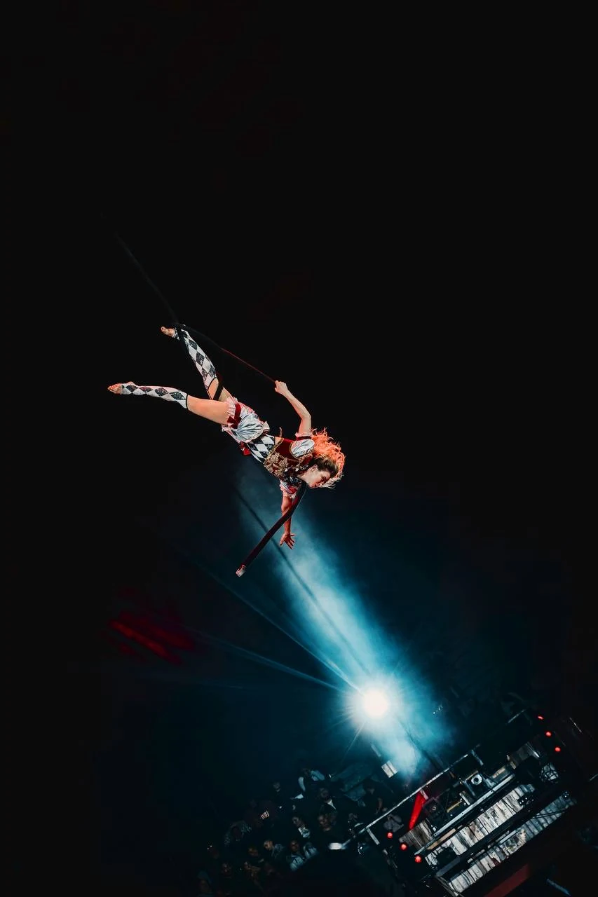 A gymnast holding a horizontal position on the rope above the circus ring